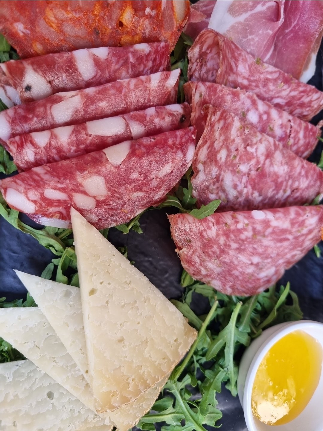 Cold cuts and cheese on arugula, with honey on the side