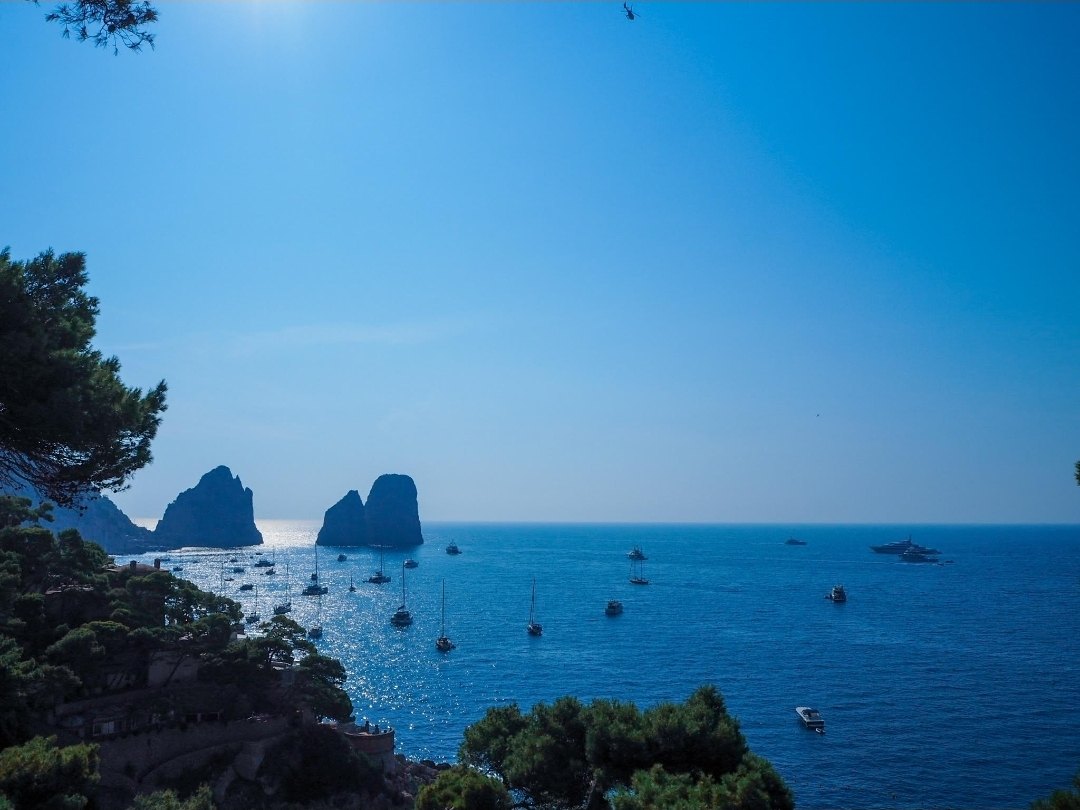 The Faraglioni and dozens of anchored boats from above