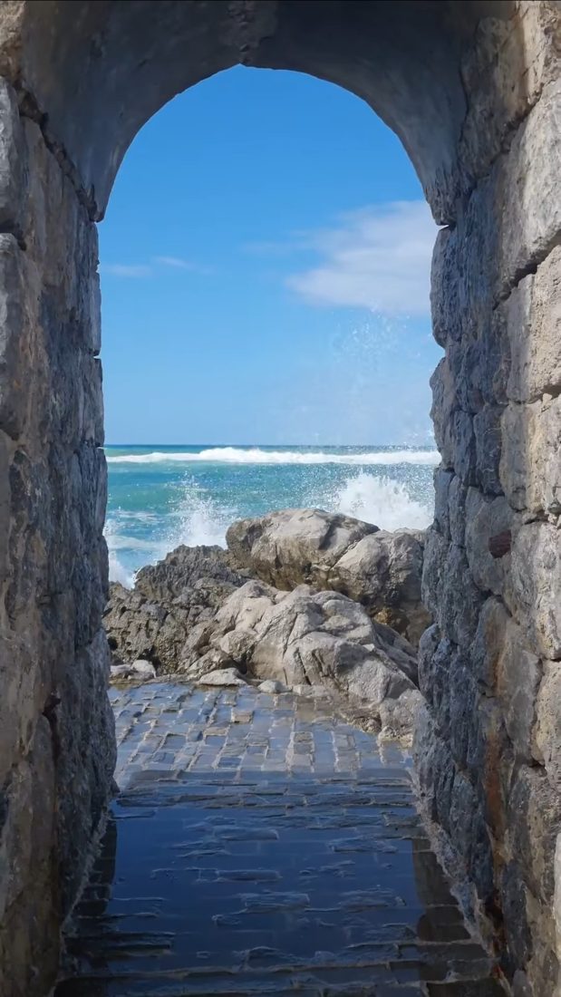 Waves and sea through a stone arch