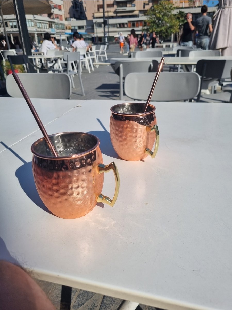 Two Moscow mules in copper mugs on a terrace table in Pescara